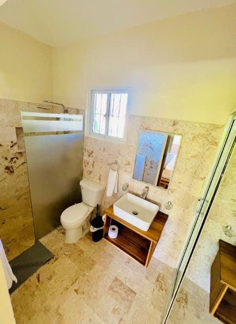 buyDRproperty Bathroom in beautiful 9-bedroom villa with stone walls, sink, toilet, and shower. Sosua Real Estate