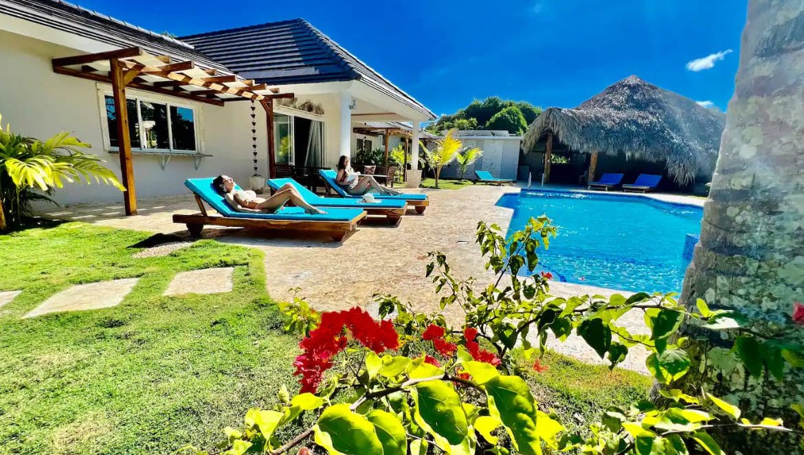 buyDRproperty Two women relaxing on sun loungers at a beautiful 9-Bedroom Villa with a pool. Sosua Real Estate