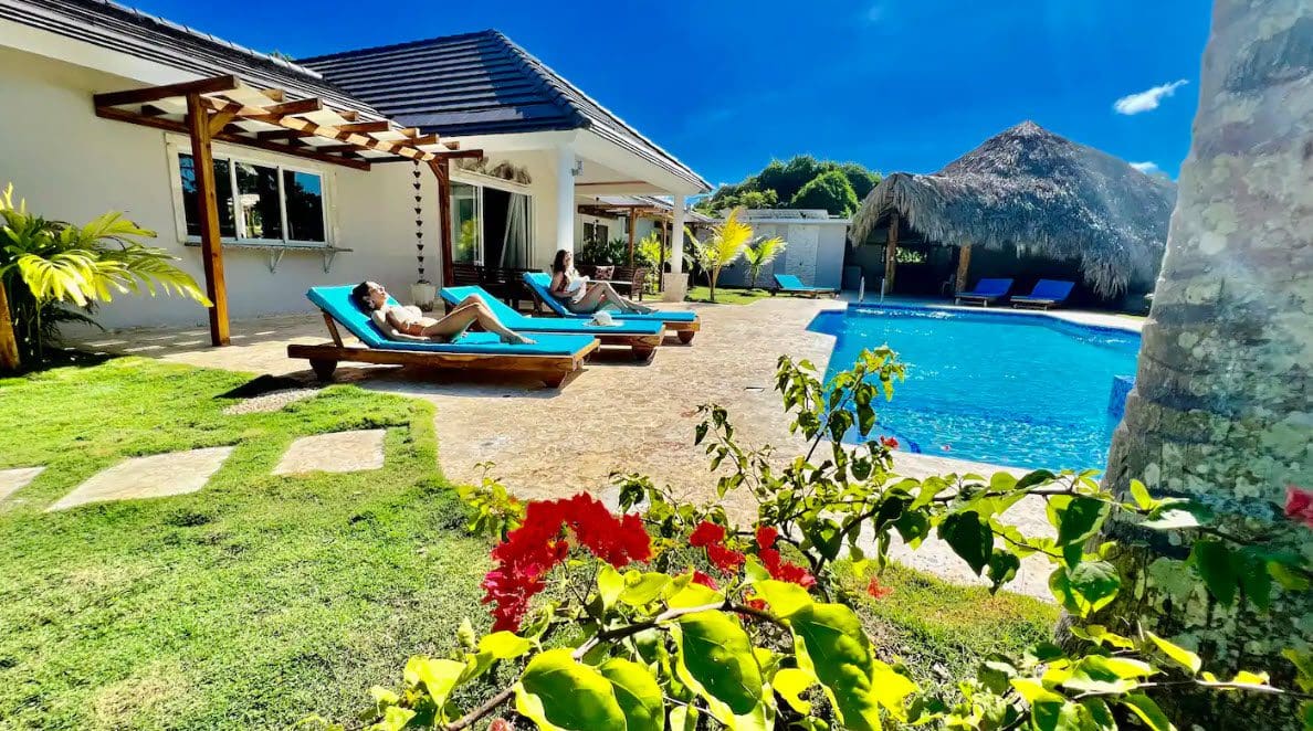 buyDRproperty Two women relaxing on sun loungers at a beautiful 9-Bedroom Villa with a pool. Sosua Real Estate