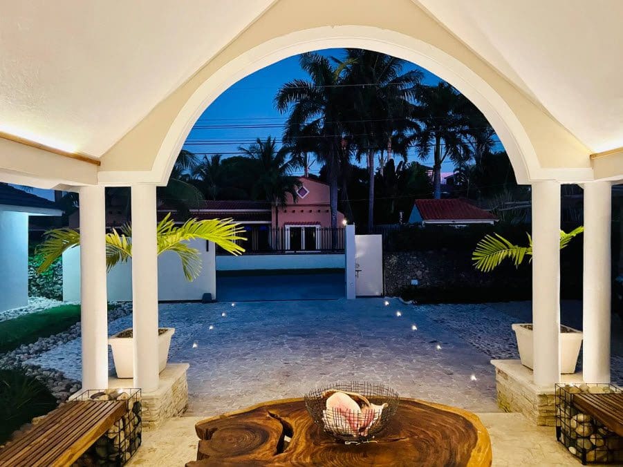 buyDRproperty Evening view of a beautiful 9-bedroom villa entrance with palm trees. Sosua Real Estate