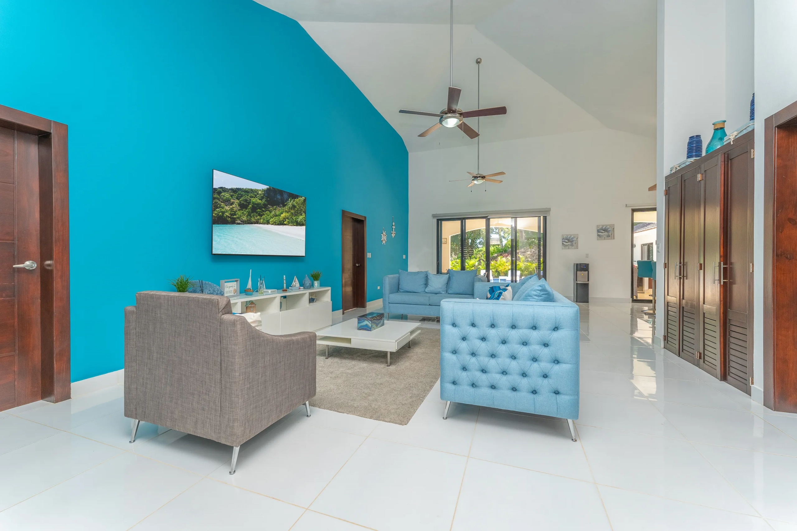 buyDRproperty Modern living room with blue accent wall, white tile, and stylish furniture. Sosua Real Estate