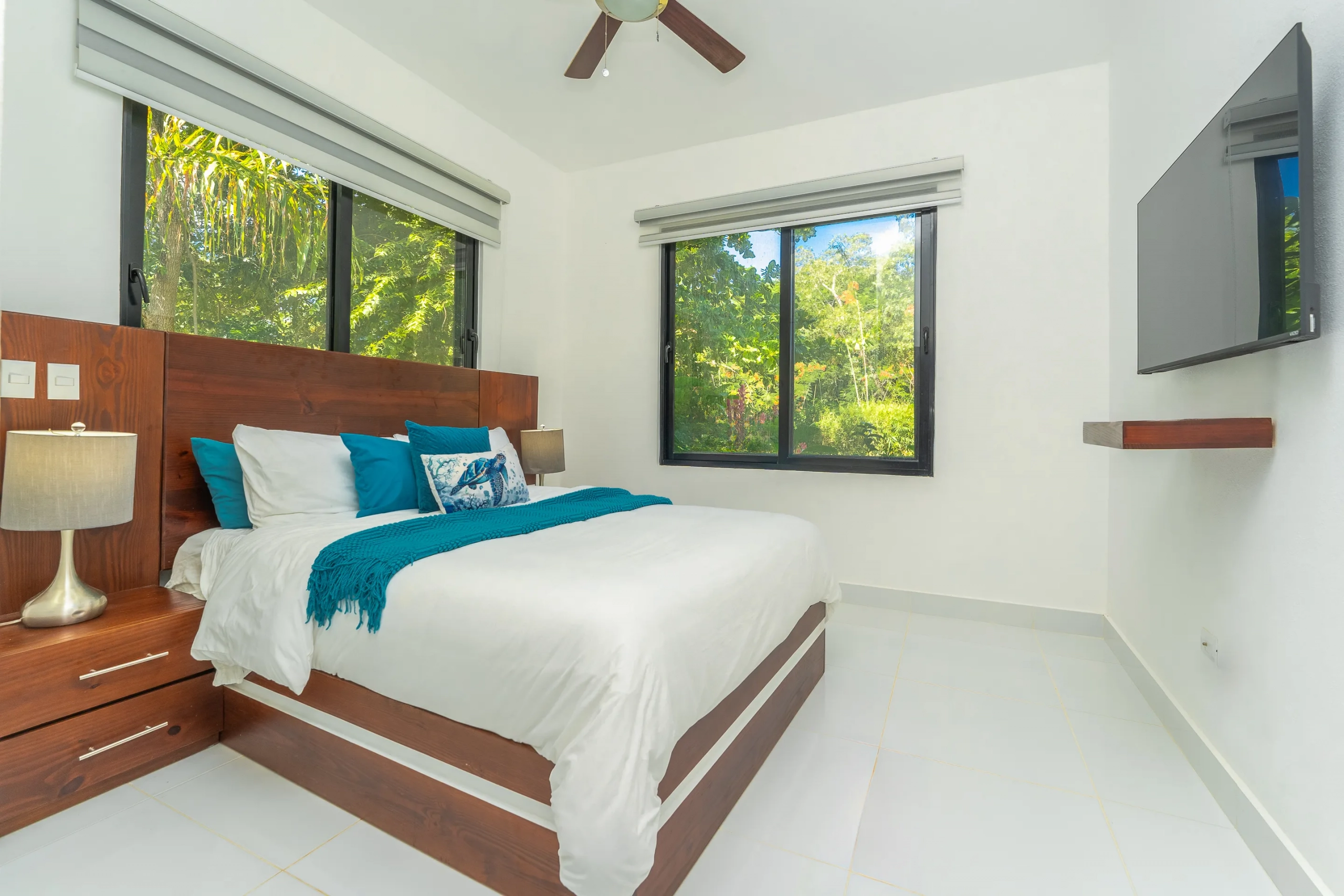 buyDRproperty Modern bedroom with a king-size bed, large windows, and a mounted TV. Sosua Real Estate