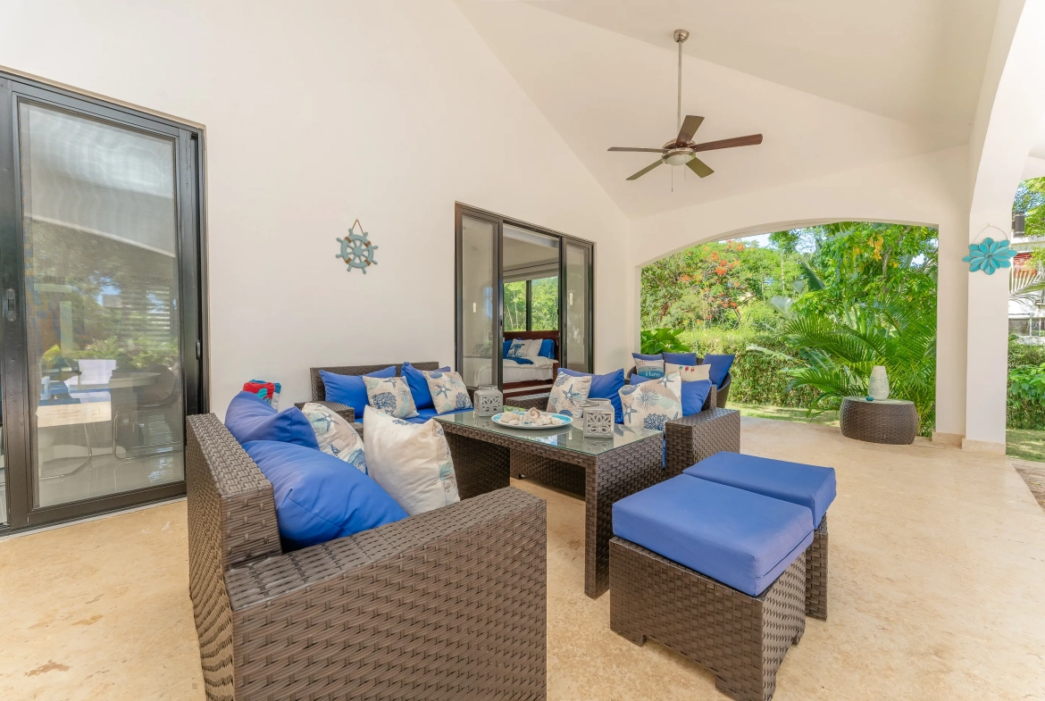 buyDRproperty Outdoor patio with wicker furniture, blue cushions, nautical decor, and garden view. Sosua Real Estate