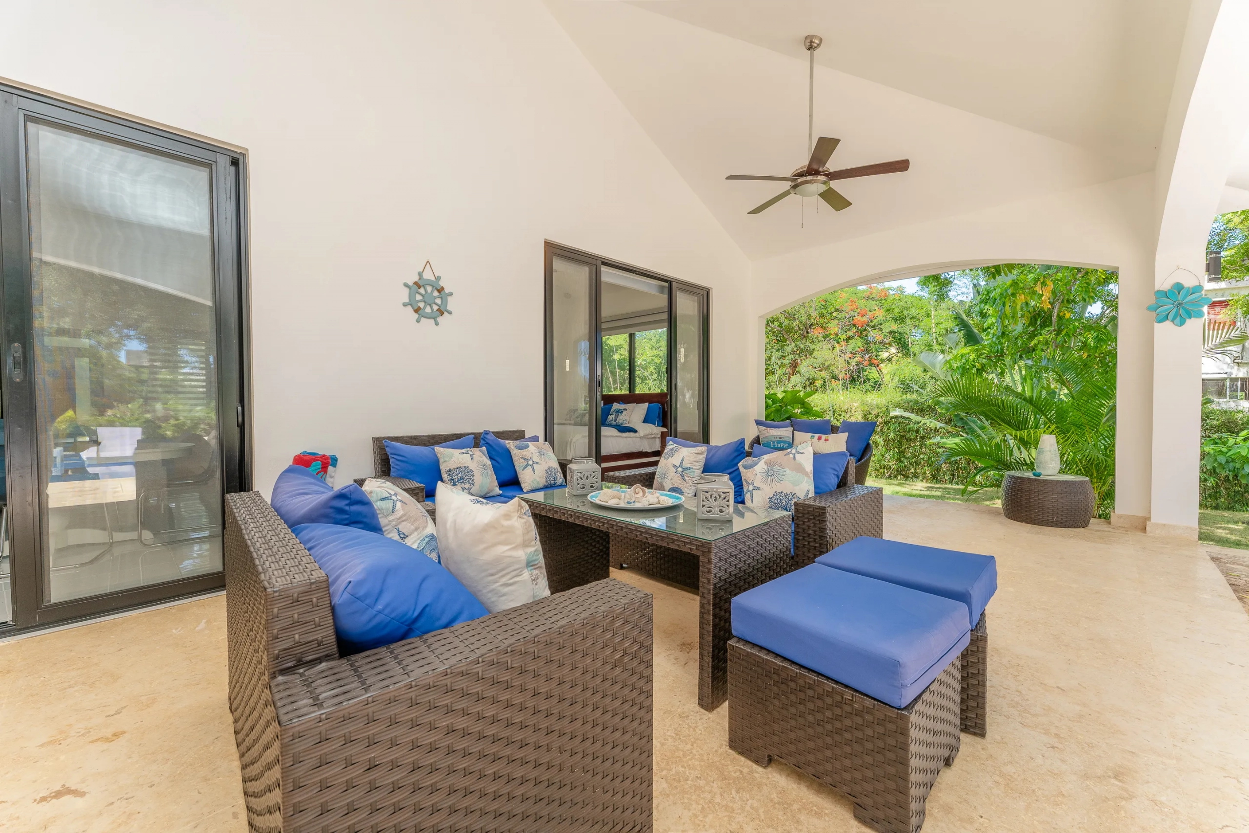 buyDRproperty Outdoor patio with wicker furniture, blue cushions, nautical decor, and garden view. Sosua Real Estate
