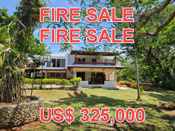 buyDRproperty Unique 4BR villa in Sosúa with "FIRE SALE" text overlay and US$325,000 price. Lush greenery surrounds the property. Sosua Real Estate