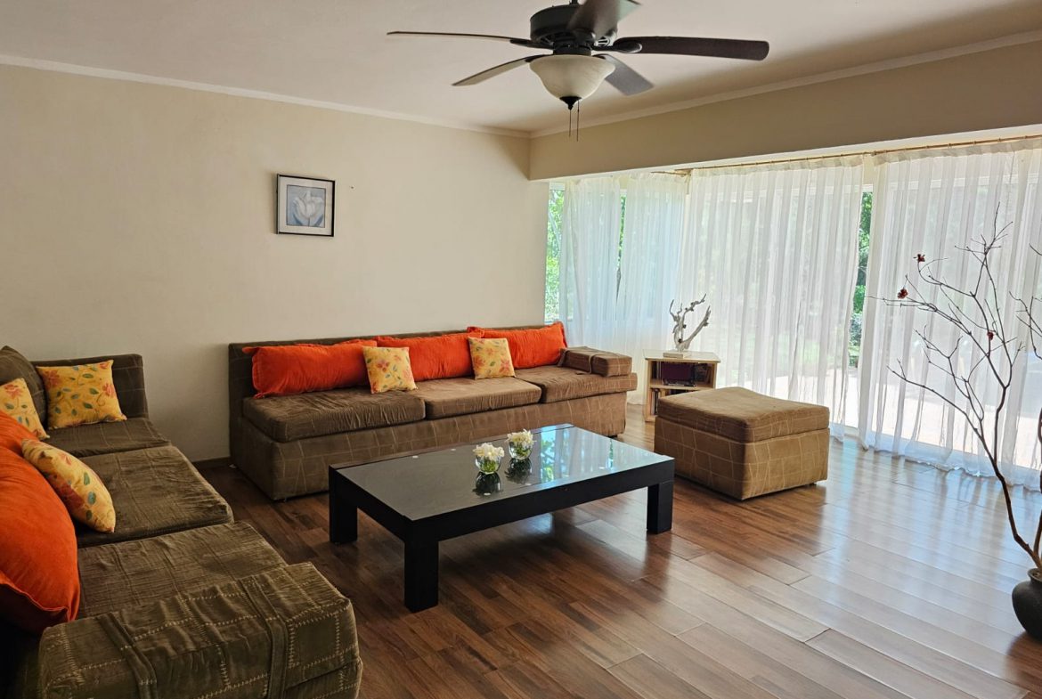 buyDRproperty Living room with brown sofas, orange pillows, and a black coffee table in a Unique Sosua villa. Sosua Real Estate