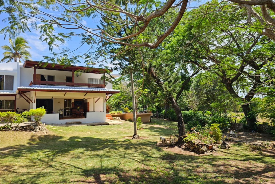 buyDRproperty Spacious villa with lawn and trees, showcasing its unique outdoor space and design. Sosua Real Estate