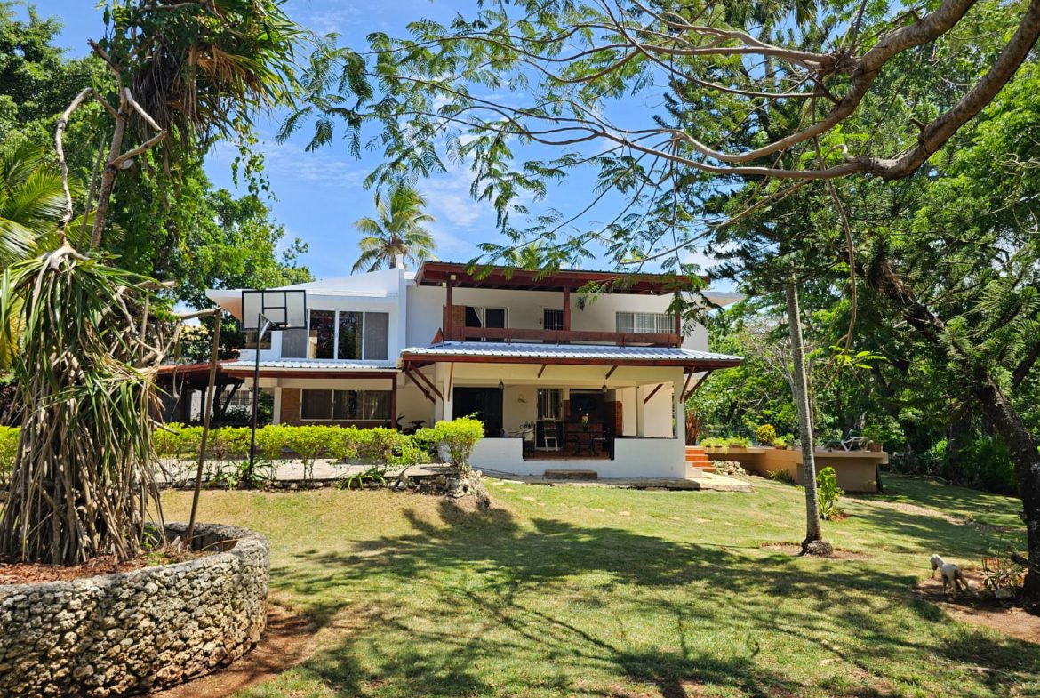 buyDRproperty Spacious villa with a large lawn and trees, showcasing its unique architecture and beautiful views. Sosua Real Estate