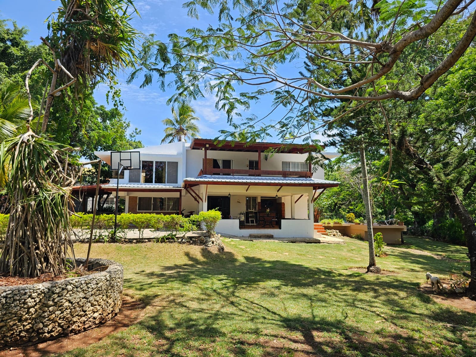 buyDRproperty Spacious villa with a large lawn and trees, showcasing its unique architecture and beautiful views. Sosua Real Estate