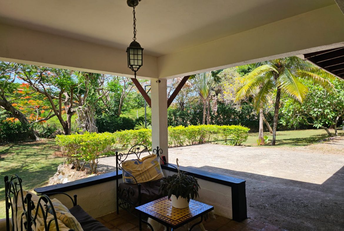 buyDRproperty Covered porch with seating at a unique Sosua villa overlooking lush tropical gardens. Sosua Real Estate