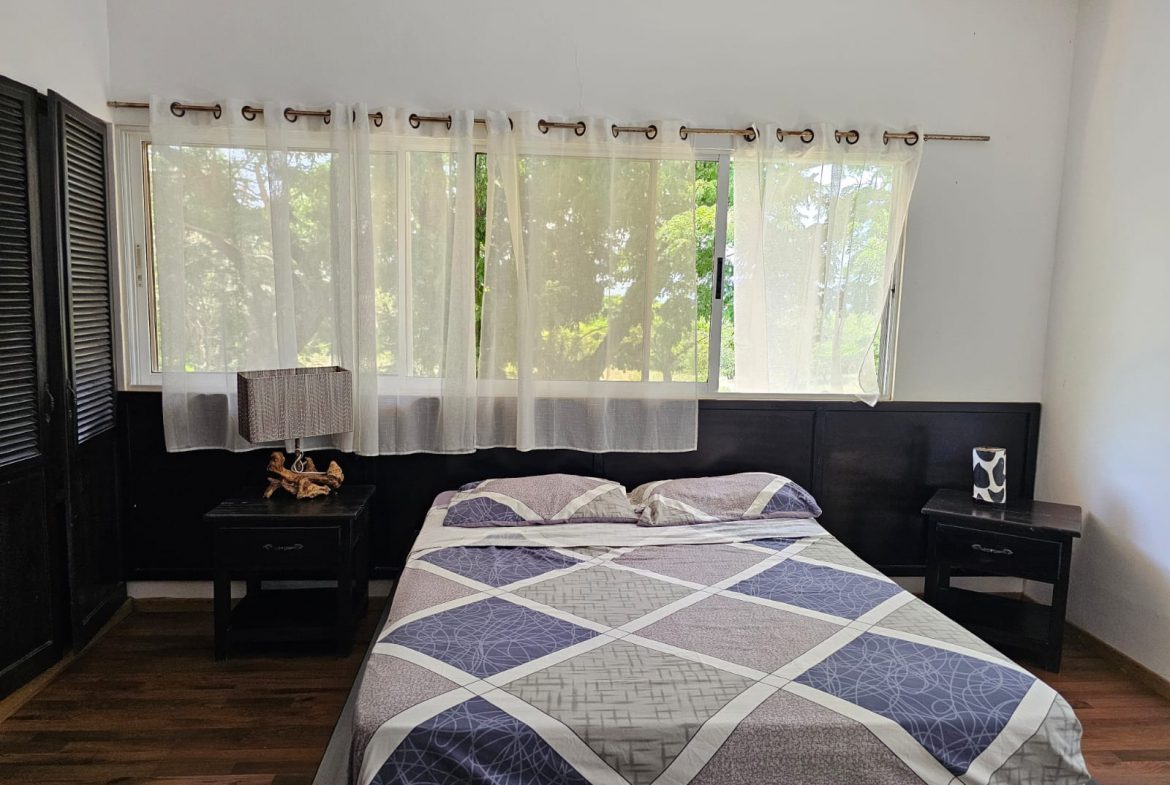 buyDRproperty Bedroom in a unique Sosua villa with a bed, nightstands, and sheer curtains, showcasing beautiful views. Sosua Real Estate