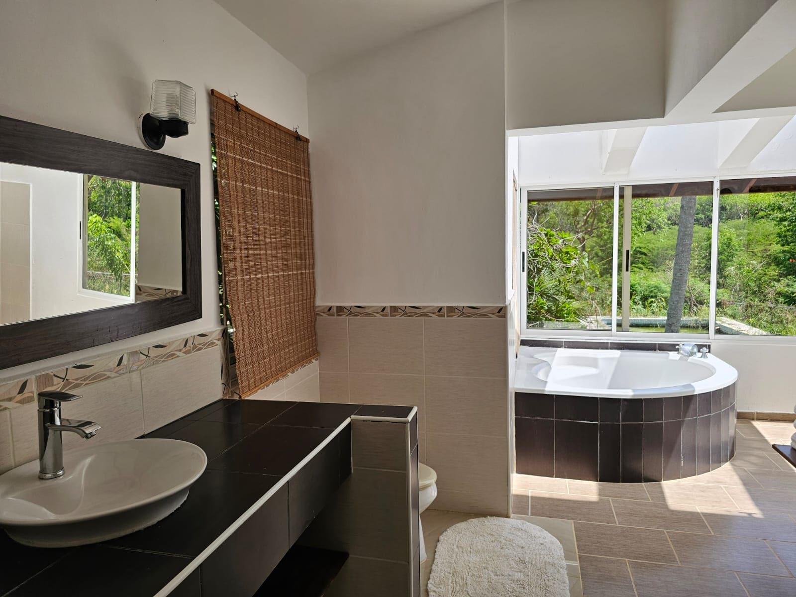 buyDRproperty Bathroom with a unique tub overlooking lush greenery, part of a spacious Sosua villa. Sosua Real Estate