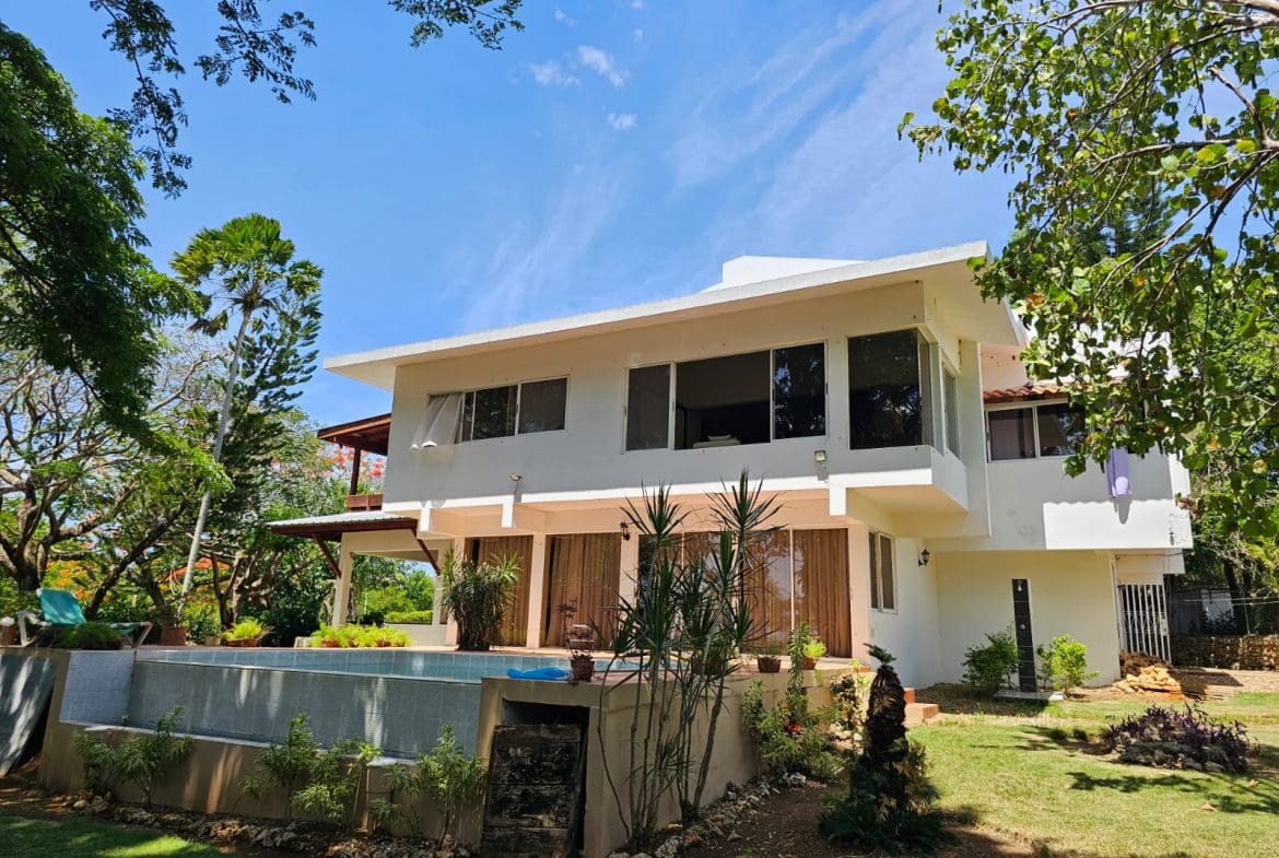 buyDRproperty Exterior view of a unique Sosua villa with a pool and beautiful landscaping. Sosua Real Estate