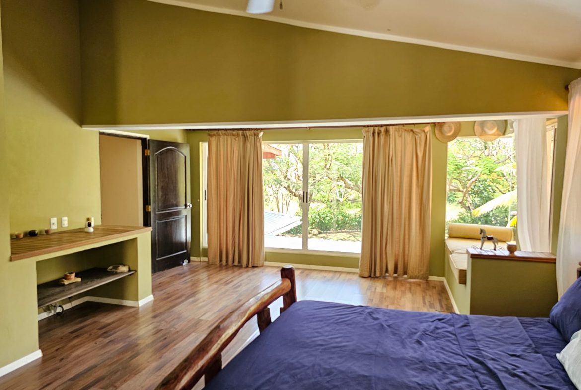 buyDRproperty Spacious bedroom with a large window showcasing beautiful outdoor views, part of a unique villa. Sosua Real Estate