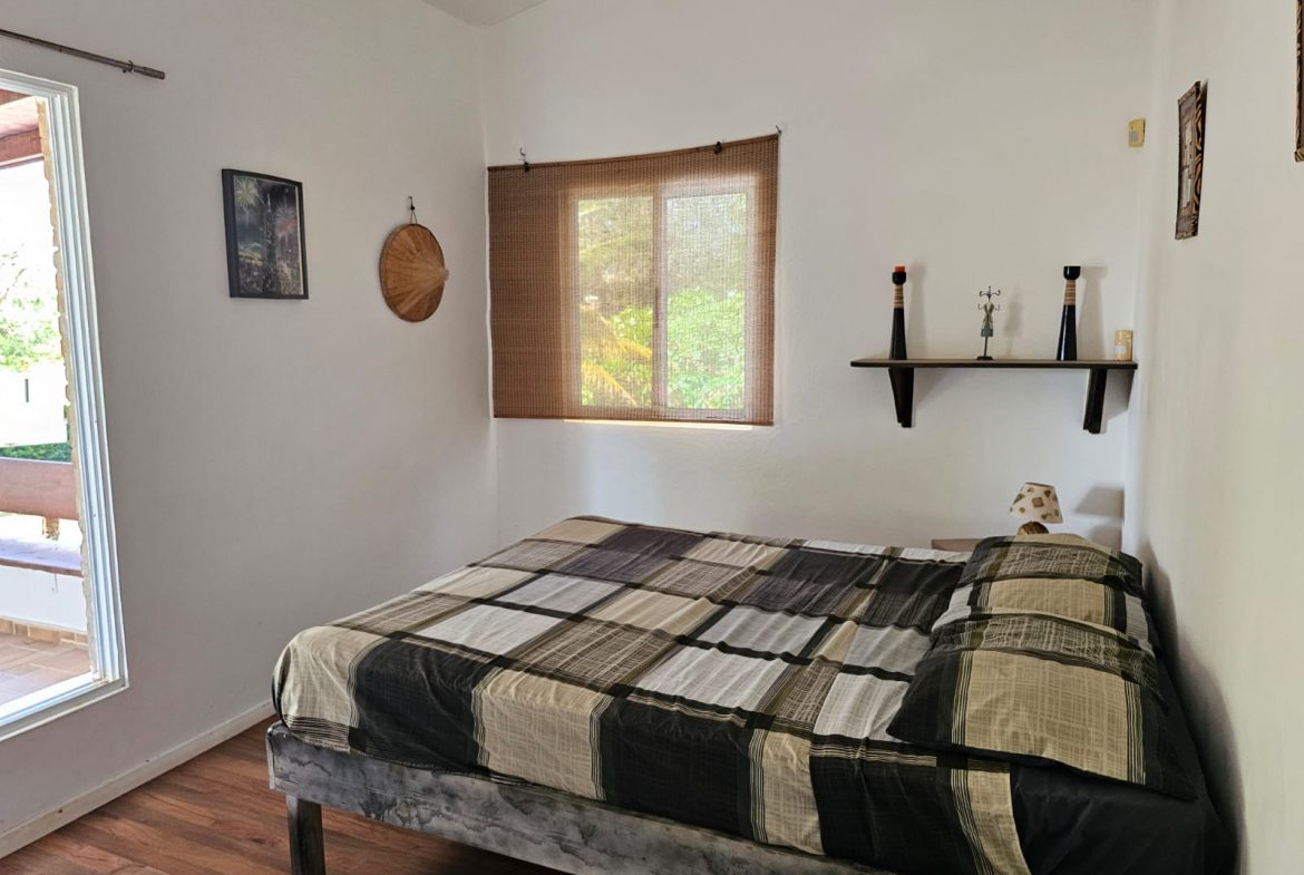 buyDRproperty Bedroom in a unique Sosua villa with a bed, window, and simple decor. Sosua Real Estate