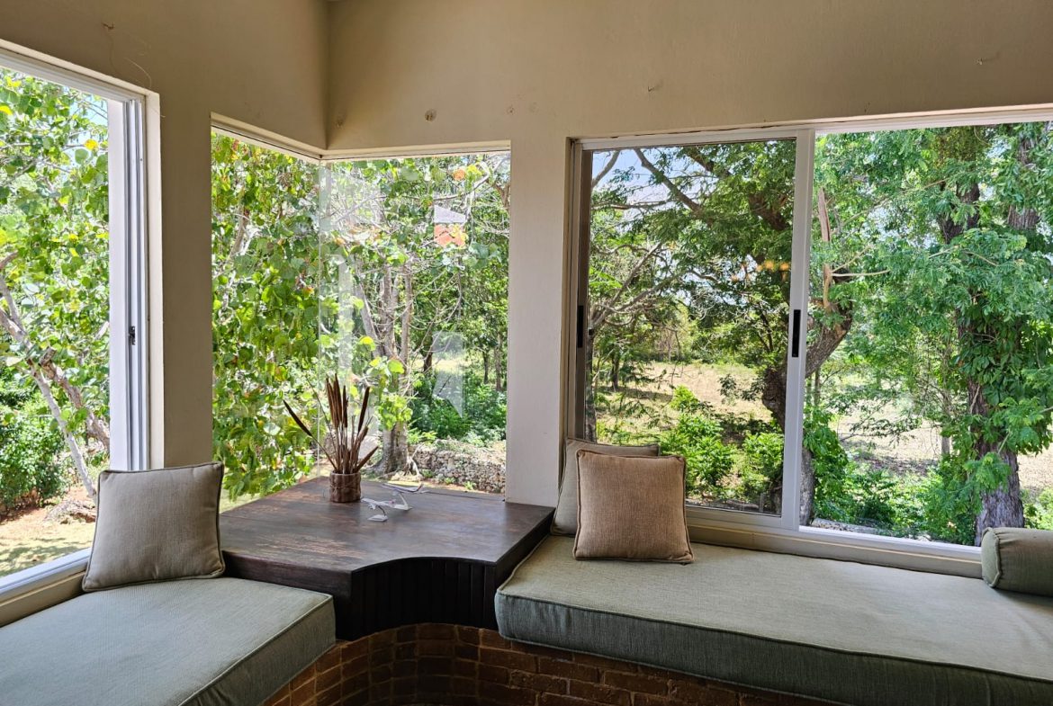 buyDRproperty Unique villa reading nook with garden view. Cushions and window seats create a cozy space. Sosua Real Estate