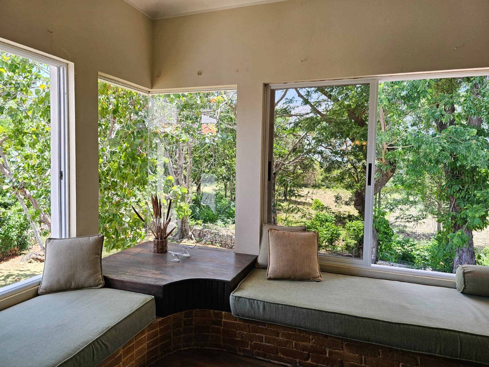 buyDRproperty Unique villa reading nook with garden view. Cushions and window seats create a cozy space. Sosua Real Estate