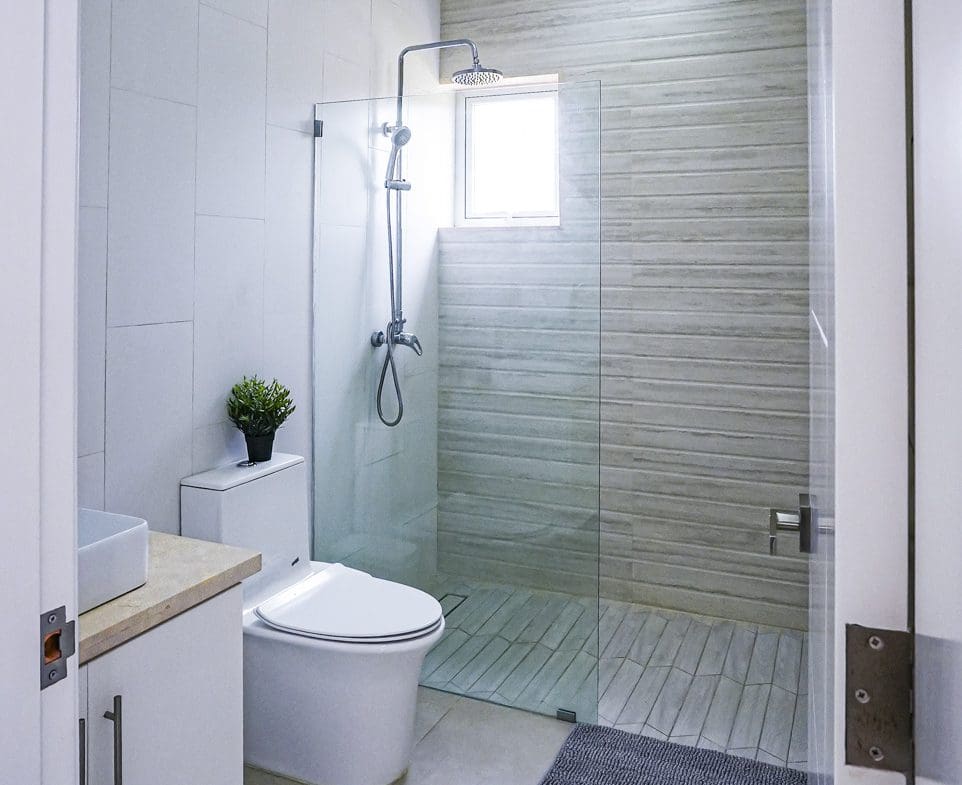 buyDRproperty Modern bathroom with glass shower, toilet, and small plant. Sosua Real Estate