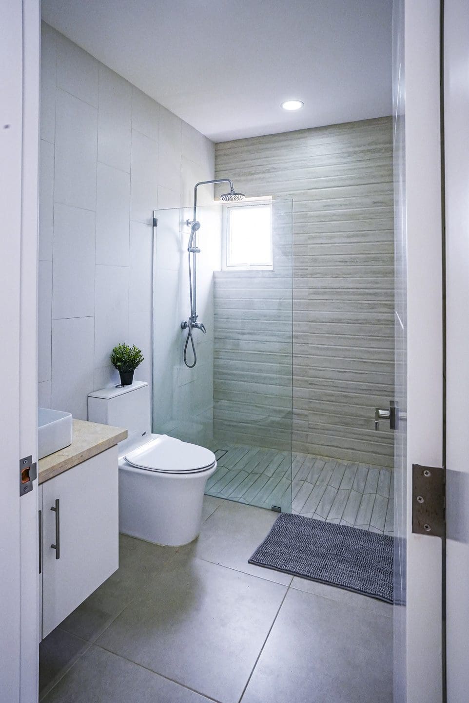 buyDRproperty Modern bathroom with glass shower, toilet, and small plant. Sosua Real Estate