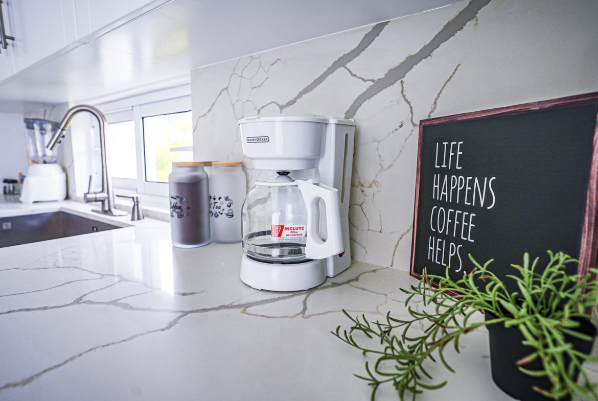 buyDRproperty Modern kitchen countertop with coffee maker and "Life Happens Coffee Helps" sign. Sosua Real Estate