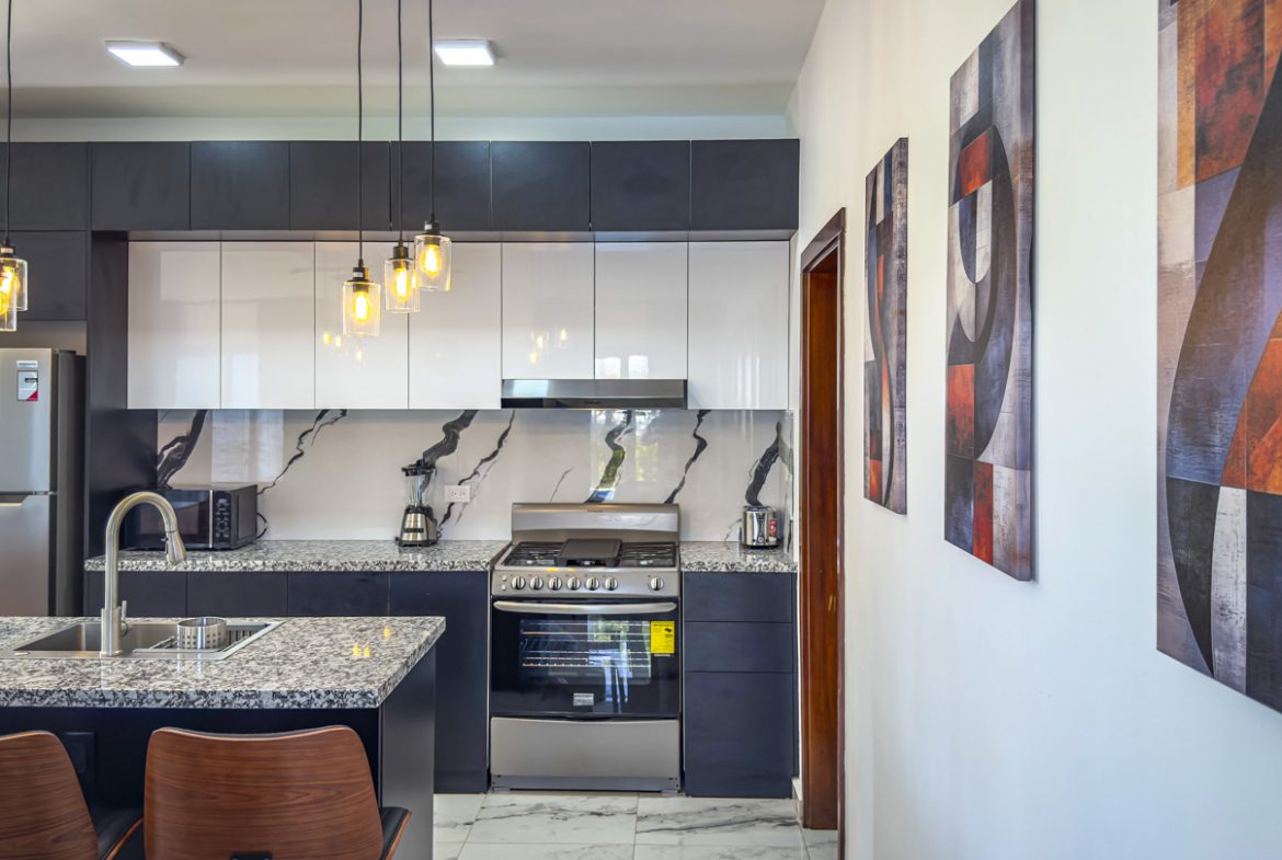 buyDRproperty Modern kitchen in a 3BR Villa Sosua Ocean Village with granite countertops and pendant lighting. Sosua Real Estate