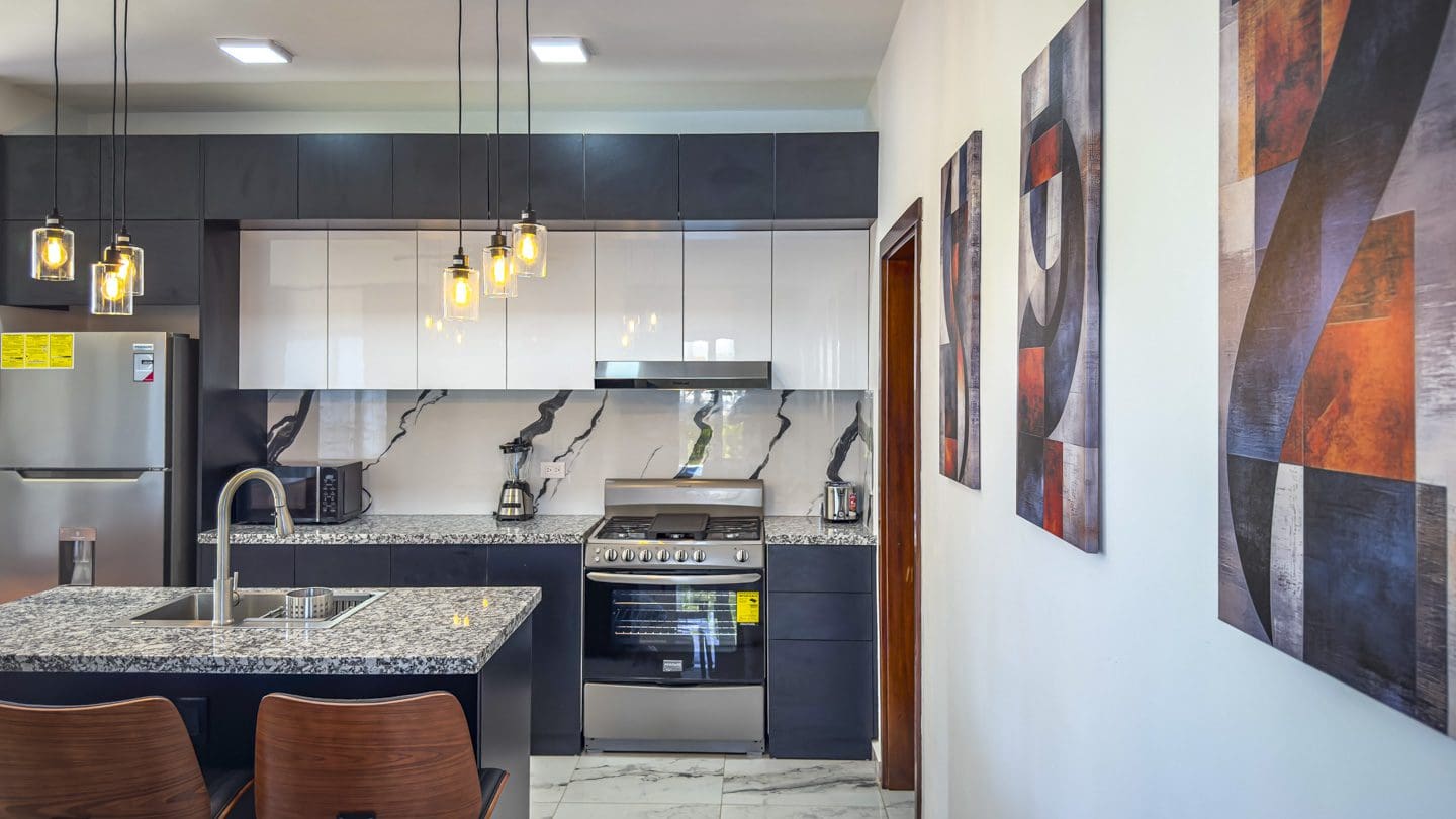 buyDRproperty Modern kitchen in a 3BR Villa Sosua Ocean Village with granite countertops and pendant lighting. Sosua Real Estate