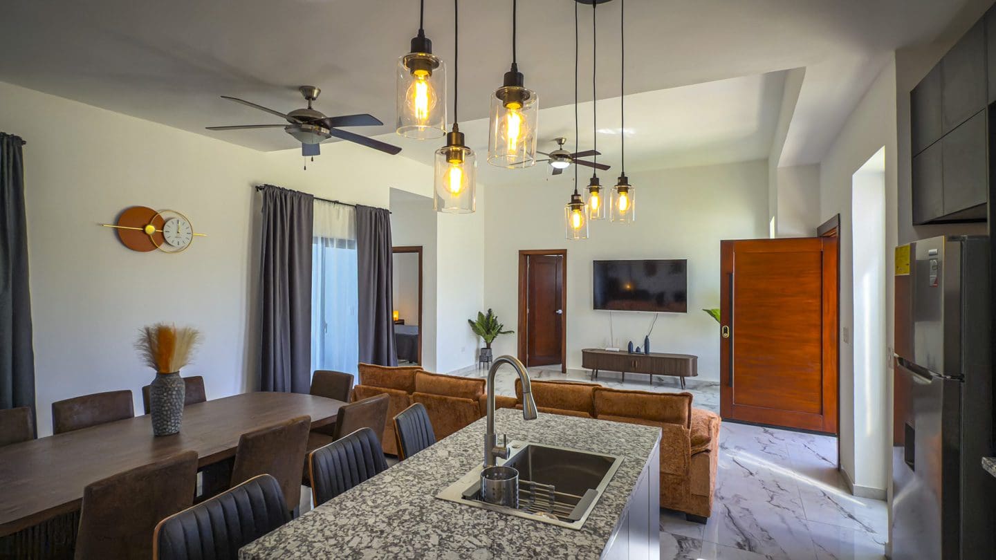 buyDRproperty Modern villa interior with kitchen island, dining area, and living room. Sosua Real Estate