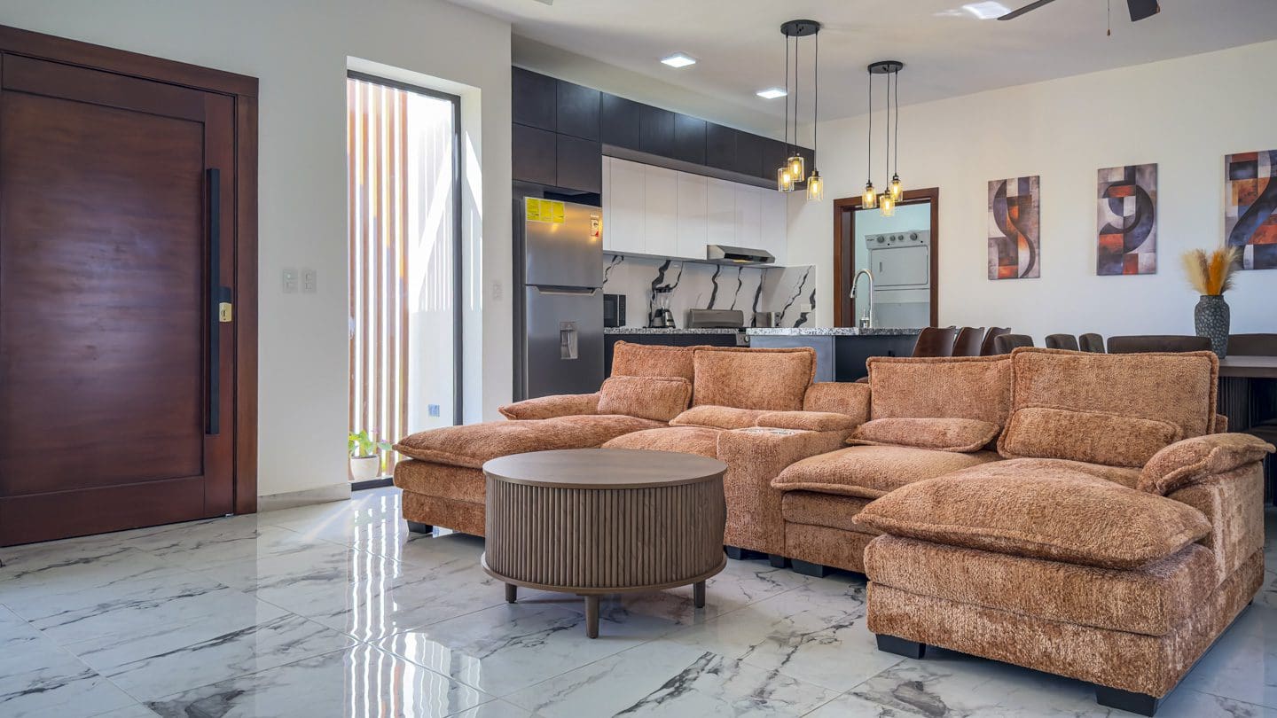 buyDRproperty Modern open-plan living room in a 3BR Villa Sosua Ocean Village with brown sectional sofa and marble flooring. Sosua Real Estate