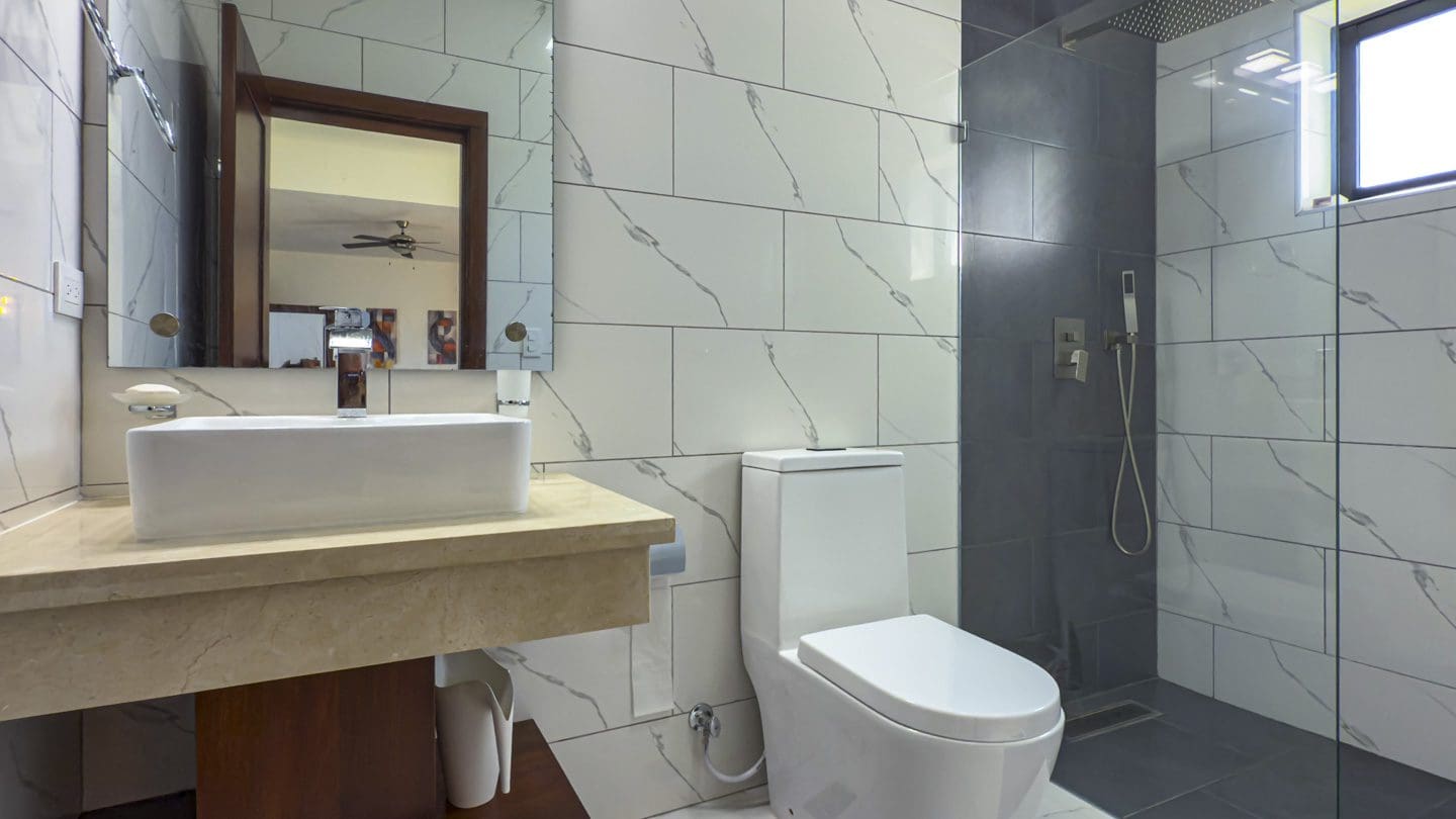 buyDRproperty Modern bathroom in a Sosua Ocean Village villa with marble-look tiles and walk-in shower. Sosua Real Estate