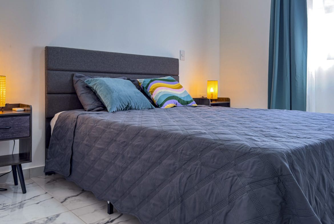 buyDRproperty Modern bedroom in a villa, featuring a large bed and stylish lamps. Sosua Real Estate