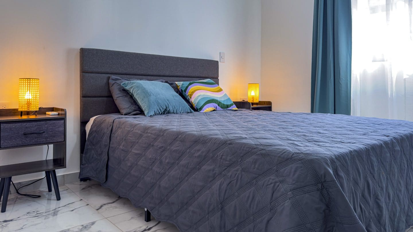 buyDRproperty Modern bedroom in a villa, featuring a large bed and stylish lamps. Sosua Real Estate