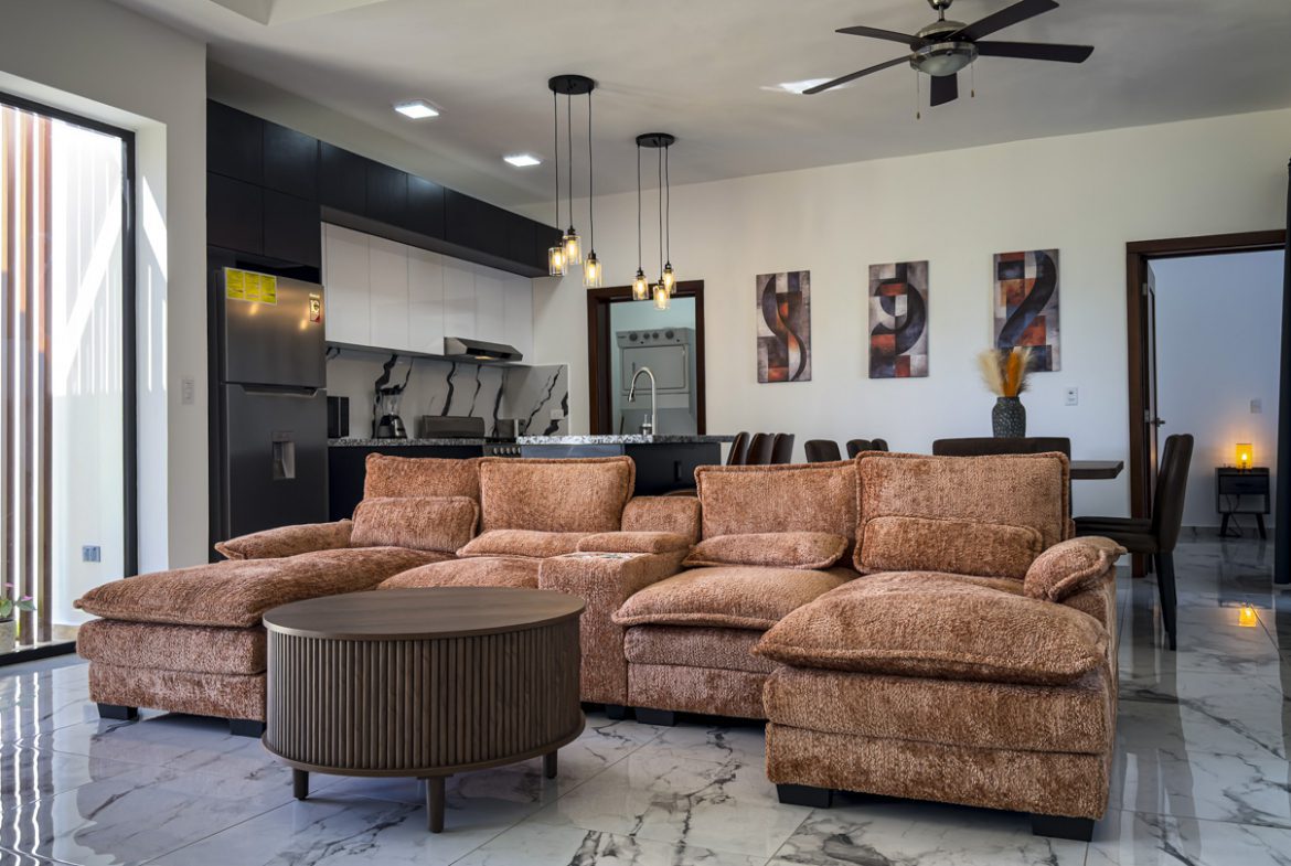 buyDRproperty Modern living room in a Sosua villa with a brown sectional sofa and a marble floor. Sosua Real Estate