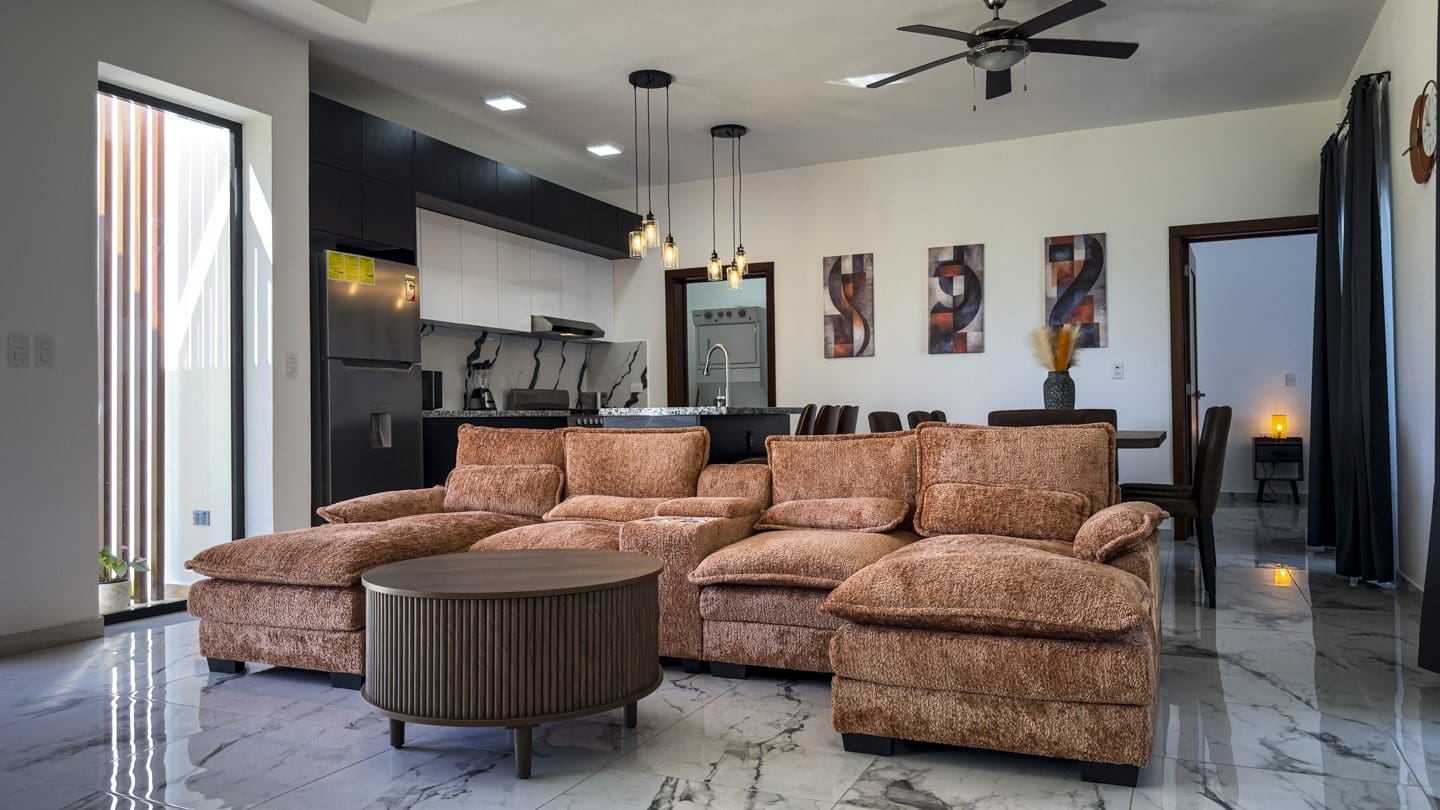 buyDRproperty Modern living room in a Sosua villa with a brown sectional sofa and a marble floor. Sosua Real Estate