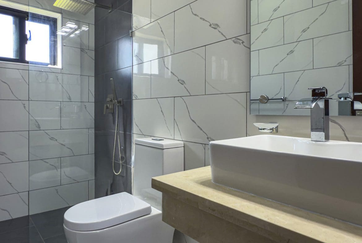 buyDRproperty Modern bathroom with white marble tiles and rectangular sink in Sosua Ocean Village villa. Sosua Real Estate