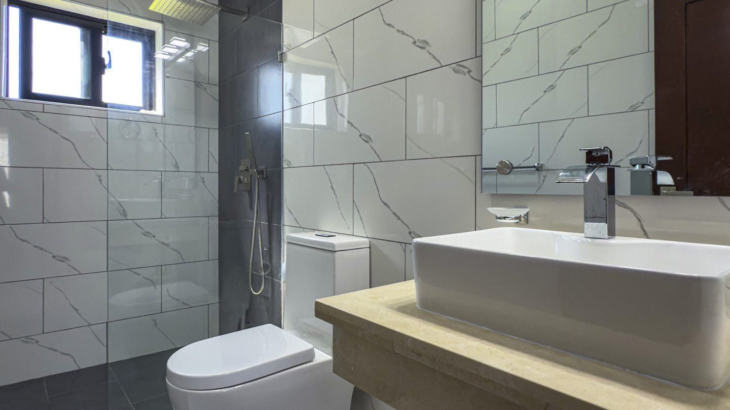 buyDRproperty Modern bathroom with white marble tiles and rectangular sink in Sosua Ocean Village villa. Sosua Real Estate