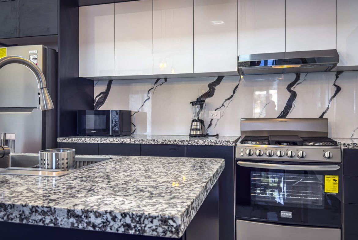 buyDRproperty Modern kitchen with white cabinets, granite countertops, and stainless steel appliances. Sosua Real Estate