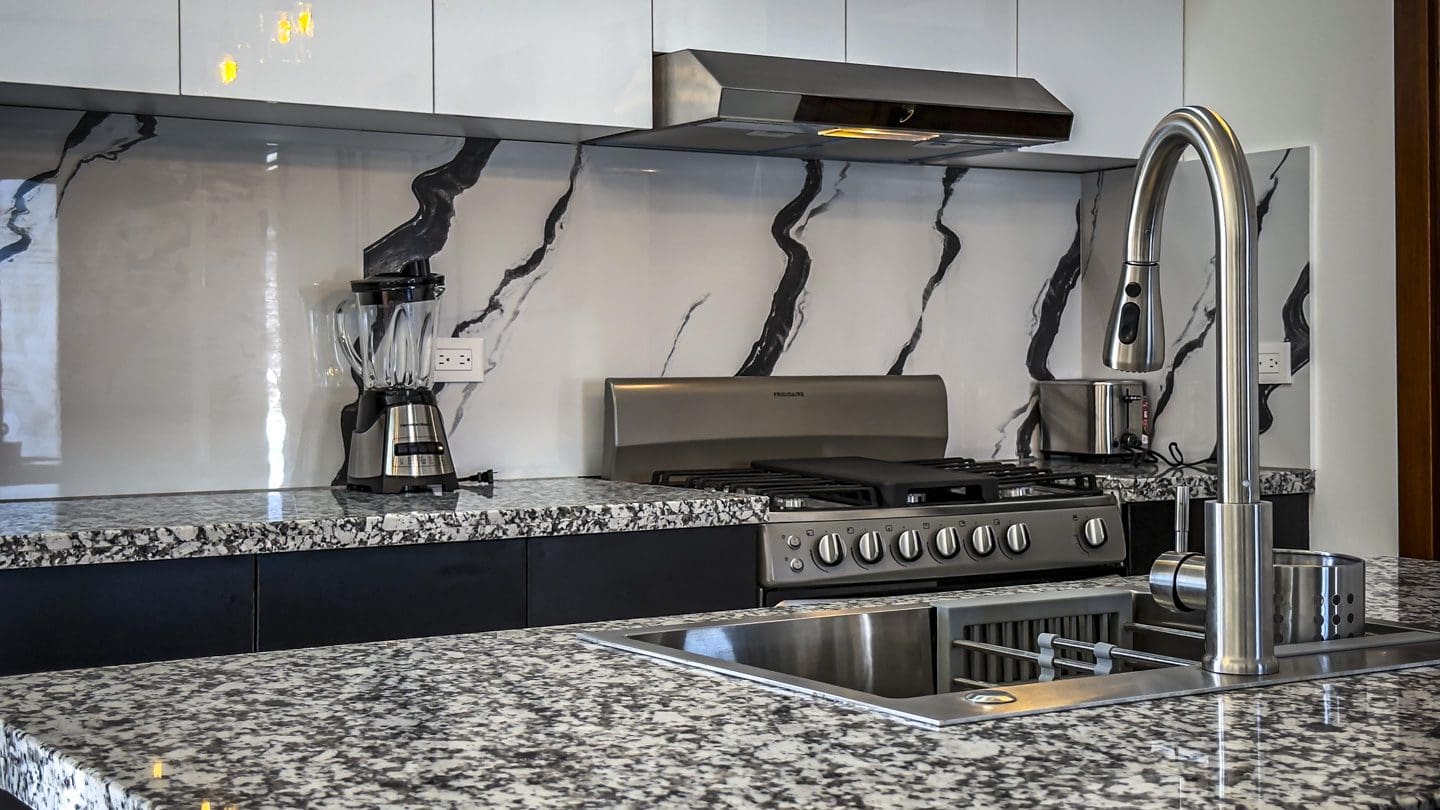 buyDRproperty Modern kitchen with granite counters, stainless steel appliances, and marble backsplash. Sosua Real Estate