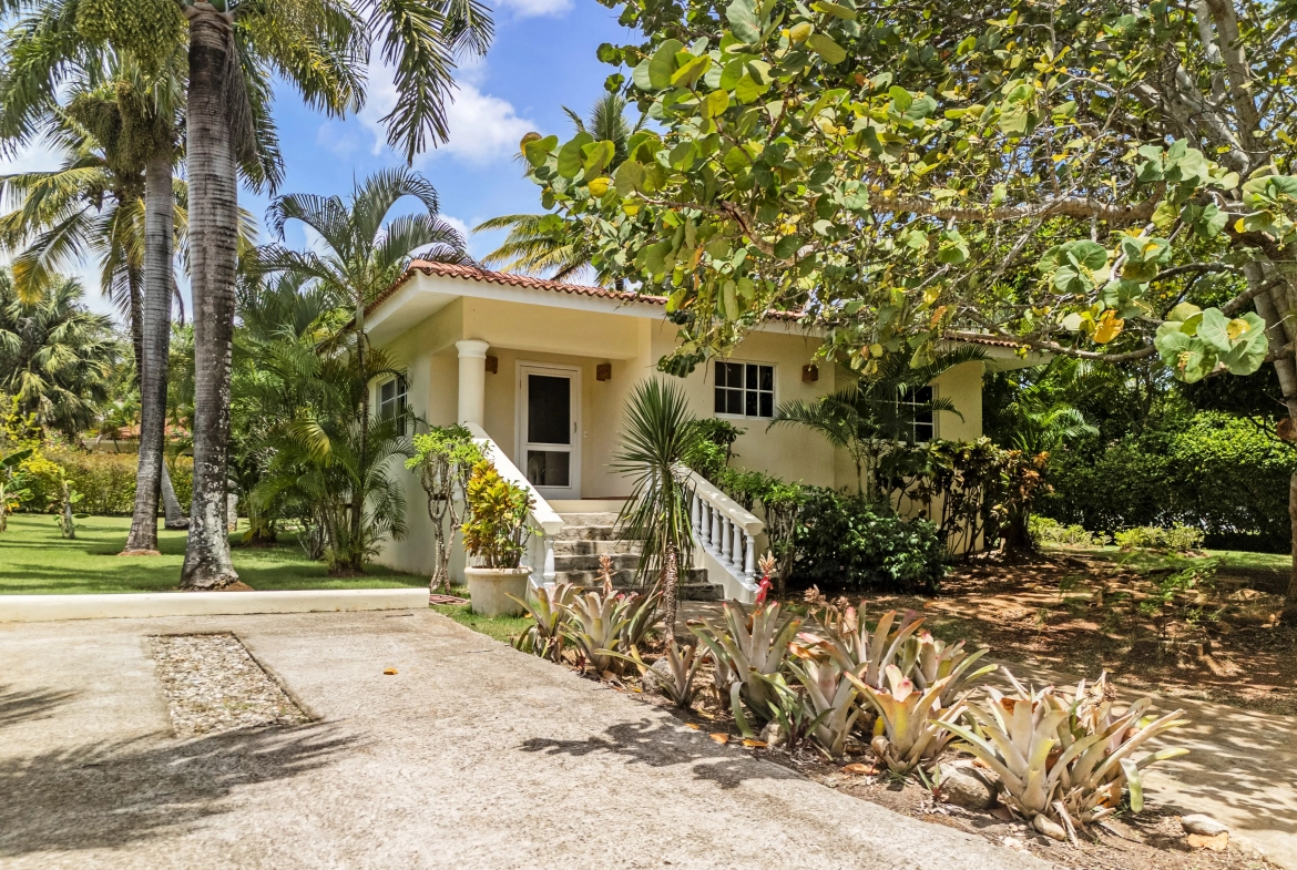 buyDRproperty Two-bedroom villa for sale in Sosua with tropical landscaping and palm trees. Sosua Real Estate