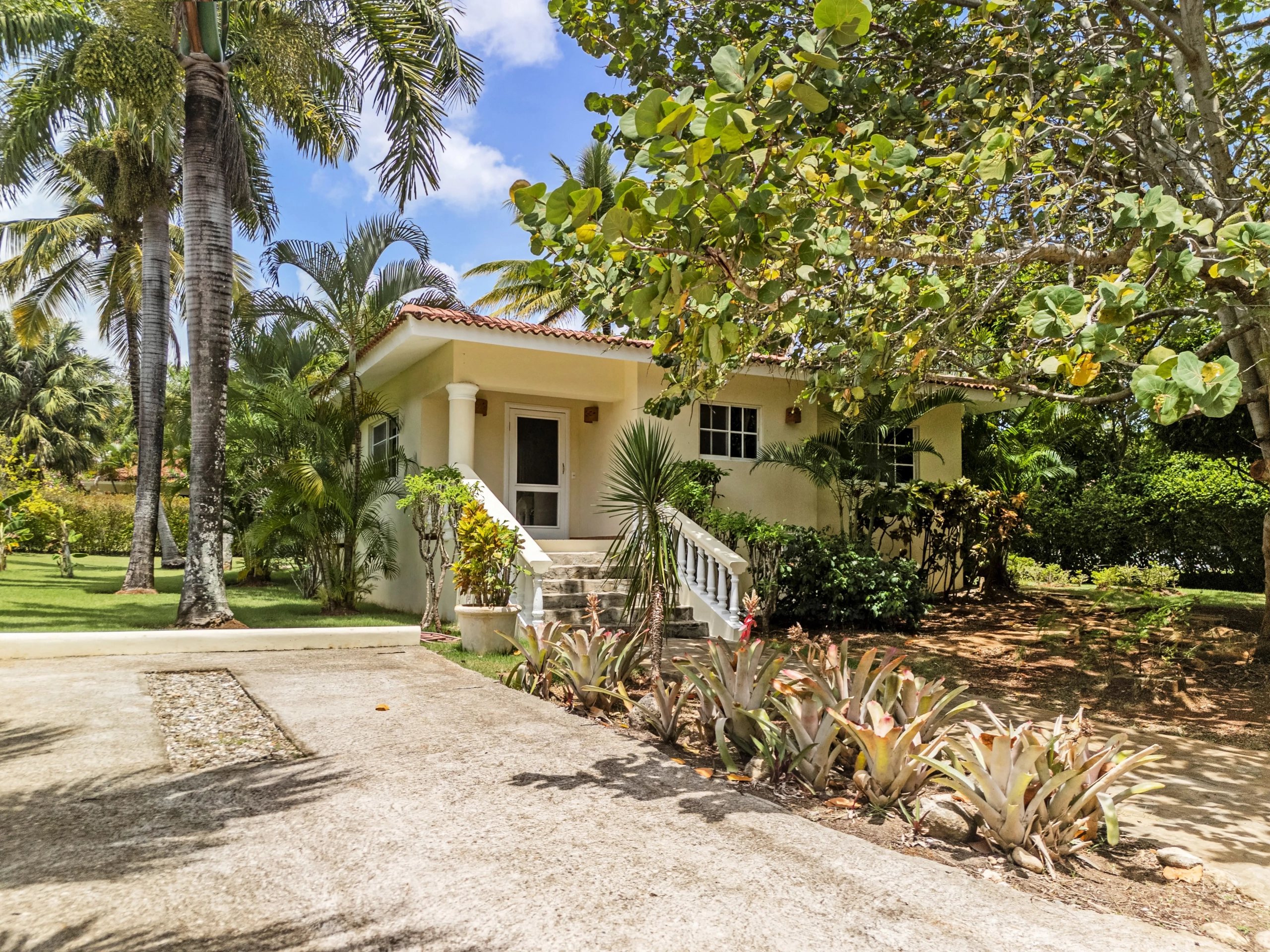 buyDRproperty Two-bedroom villa for sale in Sosua with tropical landscaping and palm trees. Sosua Real Estate
