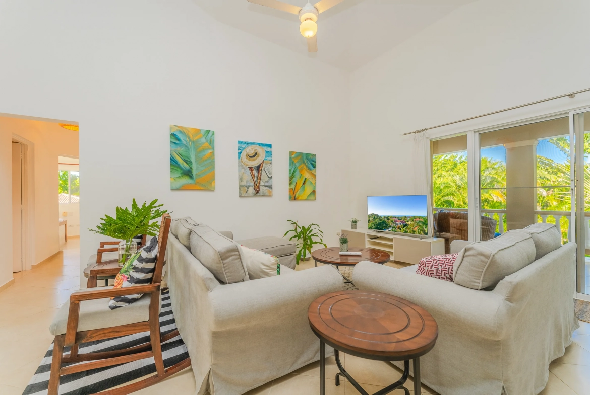buyDRproperty Living room in a beautiful 3-bedroom villa with comfortable seating, artwork, and access to a balcony. Sosua Real Estate