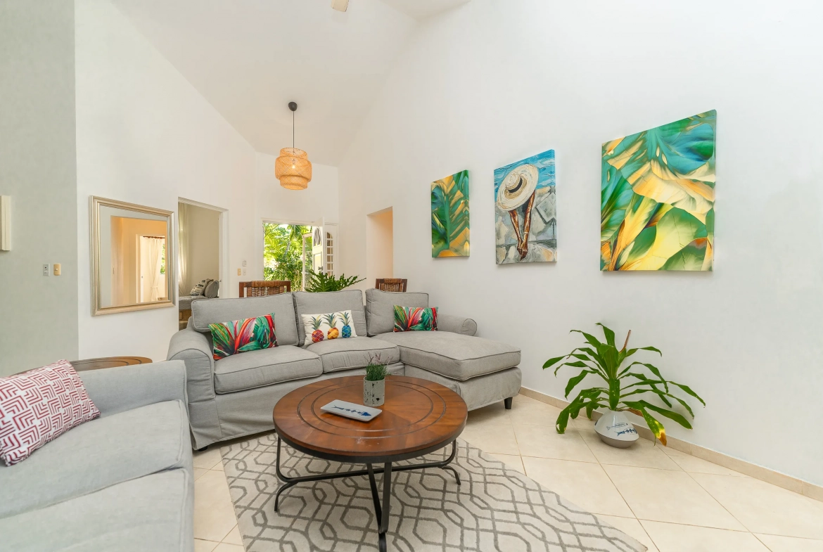 buyDRproperty Living room of a 3-bedroom villa with gray sectional sofa, artwork, and round coffee table. Sosua Real Estate