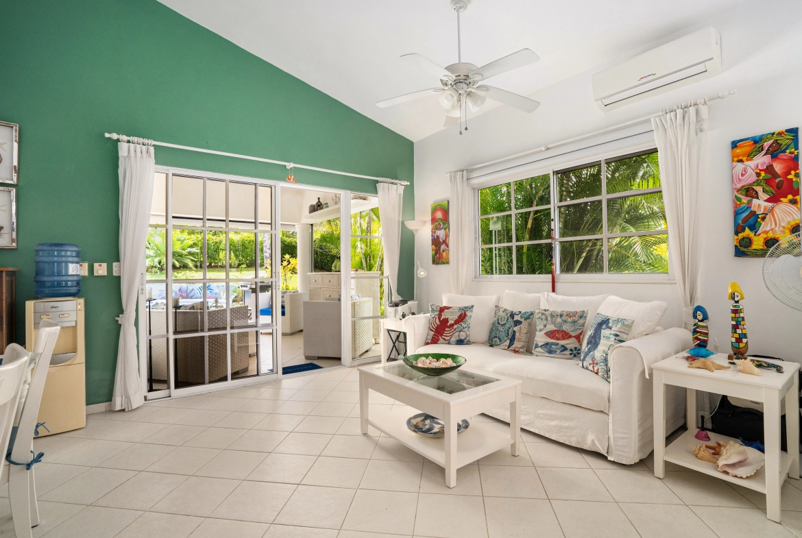 buyDRproperty Charming living room in a villa for sale in Sosua with white sofa and ocean-themed pillows. Sosua Real Estate