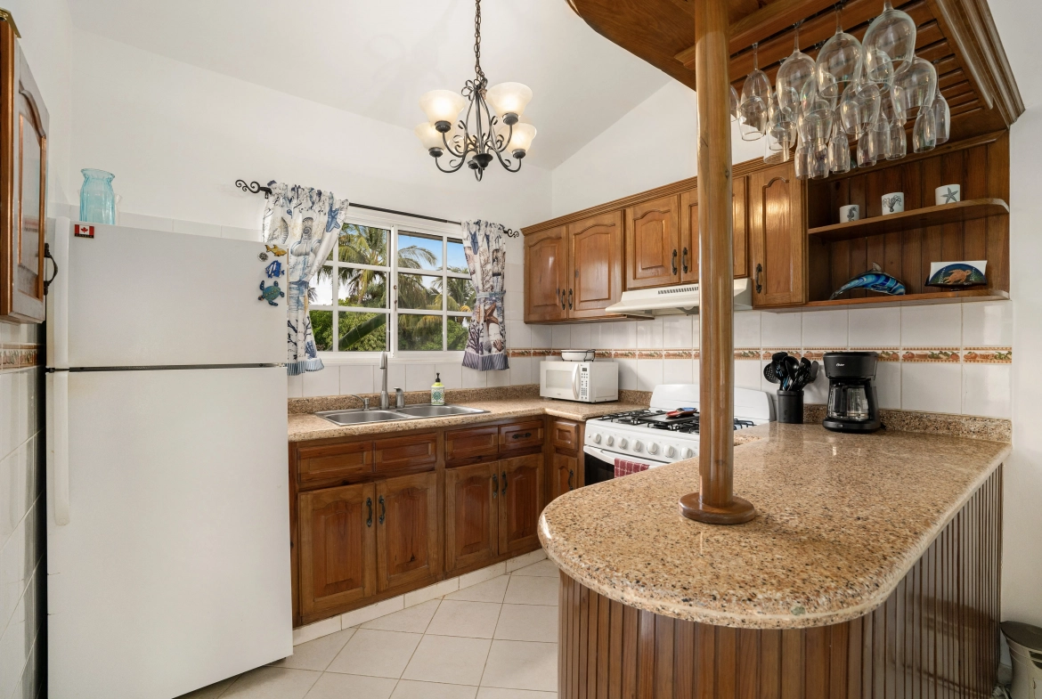 buyDRproperty Charming kitchen in a Sosua villa with wooden cabinets, granite countertop, and breakfast bar. Sosua Real Estate