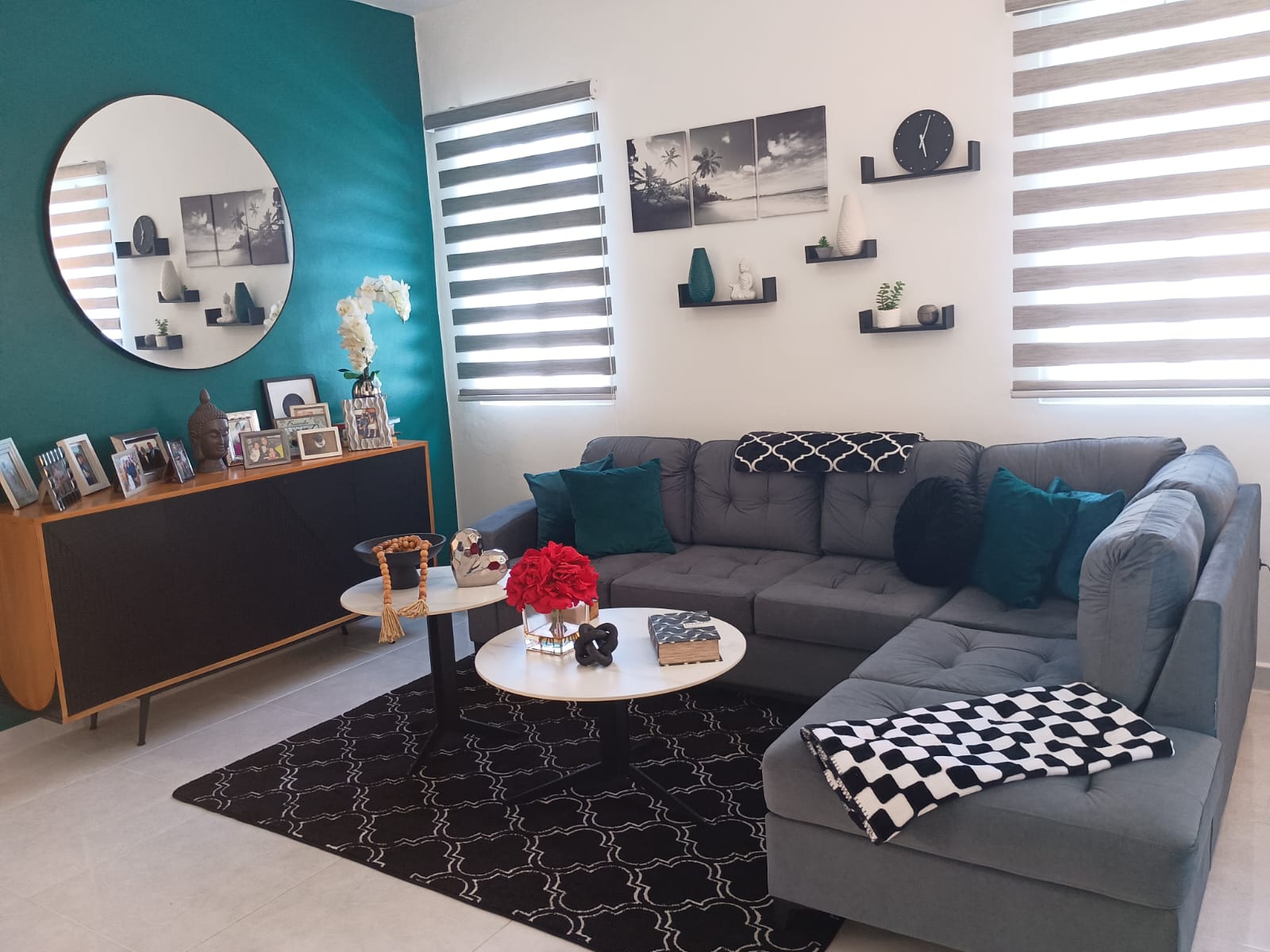 buyDRproperty Modern living room with gray sectional sofa, black rug, and teal accent wall. Sosua Real Estate