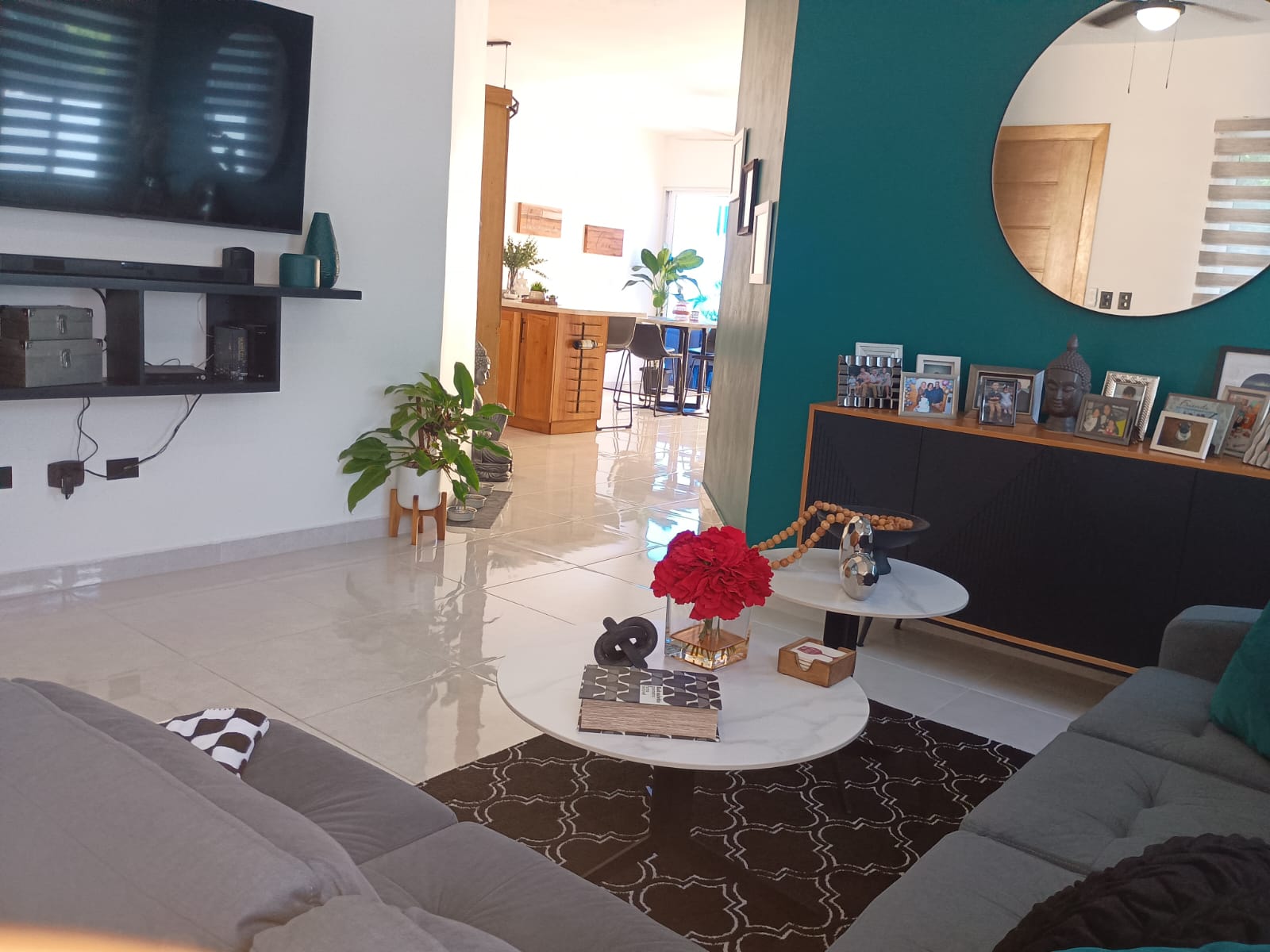 buyDRproperty Modern living room with teal accent wall and round mirror, part of a Puerto Plata villa. Sosua Real Estate