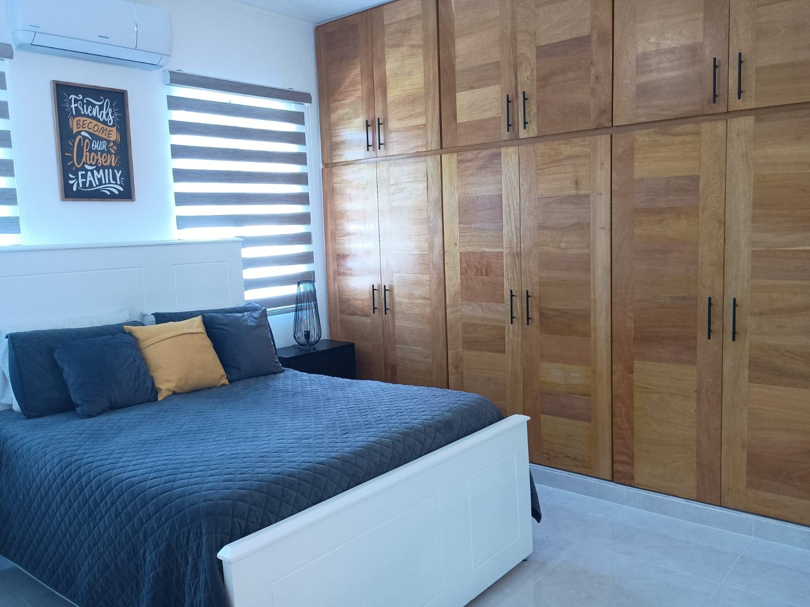 buyDRproperty Modern bedroom with large wooden wardrobes and a bed with blue bedding. Sosua Real Estate