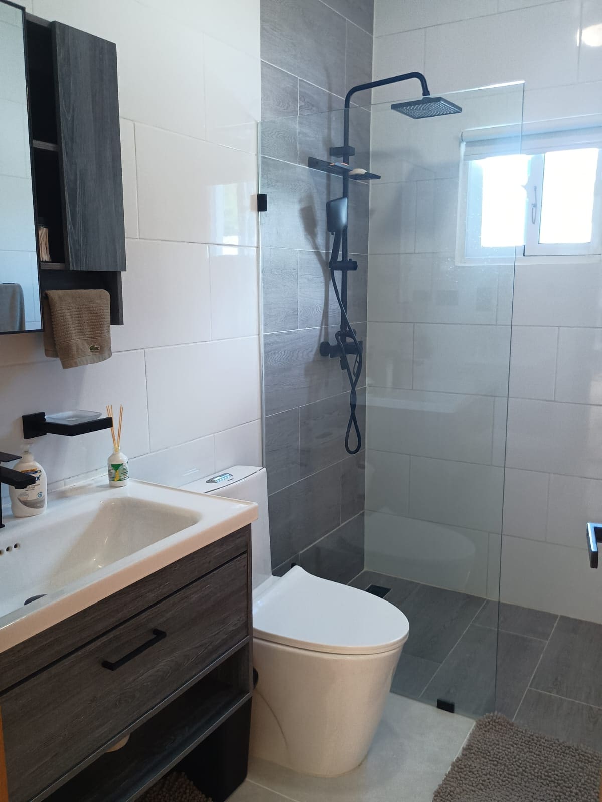 buyDRproperty Modern bathroom with gray and white tiles, glass shower and black fixtures. Sosua Real Estate