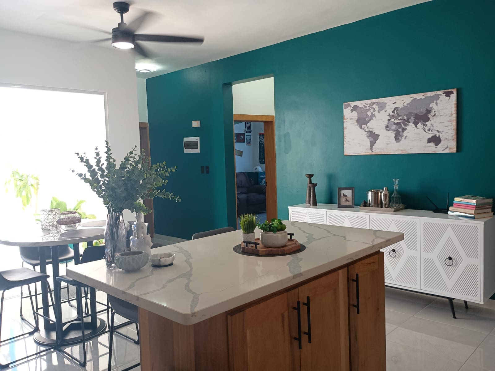 buyDRproperty Modern kitchen interior with teal accent wall, island, and white cabinets. Sosua Real Estate