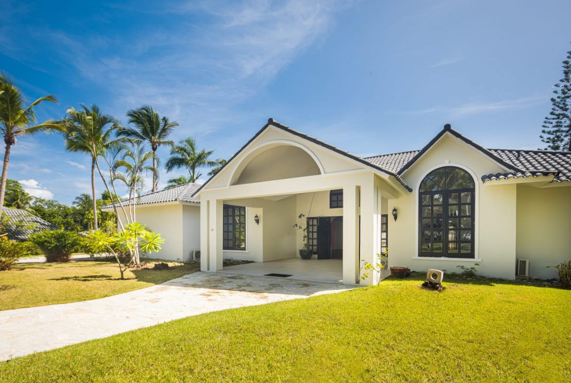 buyDRproperty White tropical home with arched doorway and lush green lawn, perfect for vacation rentals. Sosua Real Estate