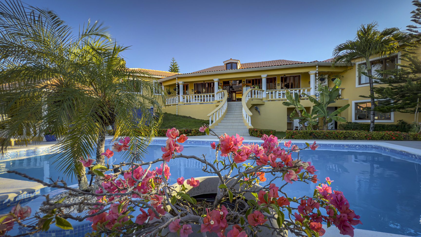 buyDRproperty Luxury villa with a pool and bougainvillea. Ocean views and a lush garden create a tropical paradise. Sosua Real Estate